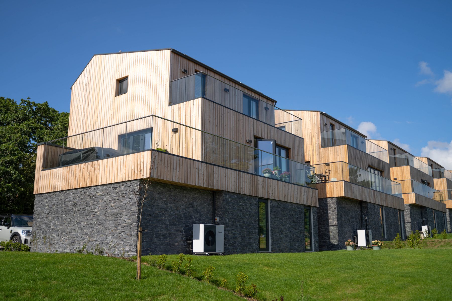 The Green — larch-clad homes on a slate plinth with air source heat pumps